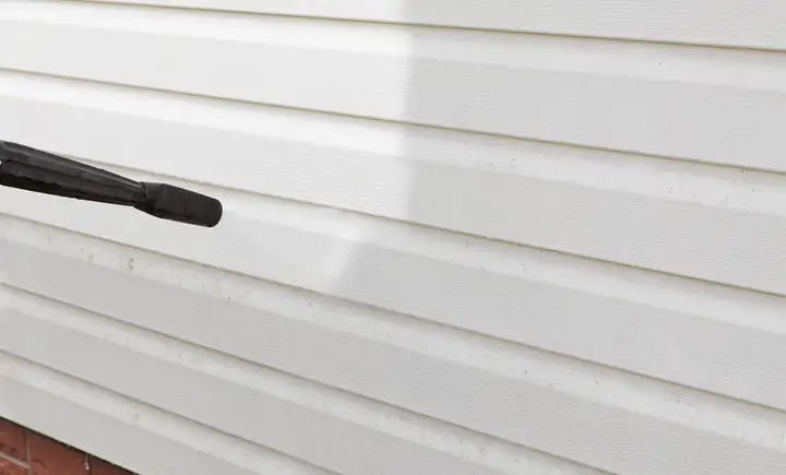 Clean white vinyl siding being rinsed at low pressure